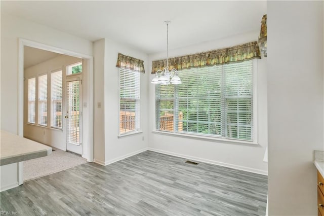 unfurnished dining area featuring hardwood / wood-style floors and a notable chandelier