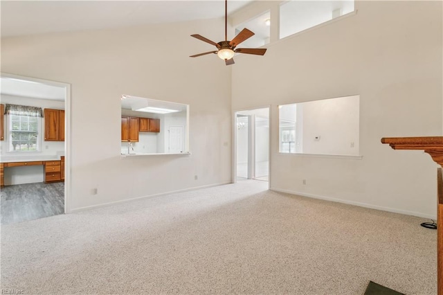 unfurnished living room with ceiling fan, beamed ceiling, high vaulted ceiling, carpet, and built in desk