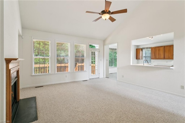 unfurnished living room featuring ceiling fan, high vaulted ceiling, and light colored carpet