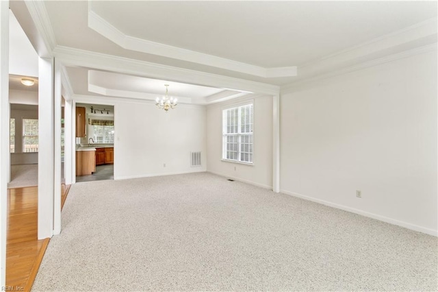 empty room featuring a raised ceiling, crown molding, light carpet, and a notable chandelier