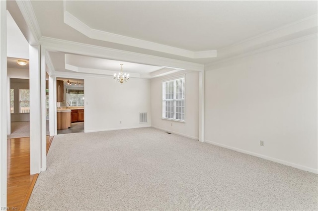 empty room featuring light carpet, a chandelier, a raised ceiling, and crown molding