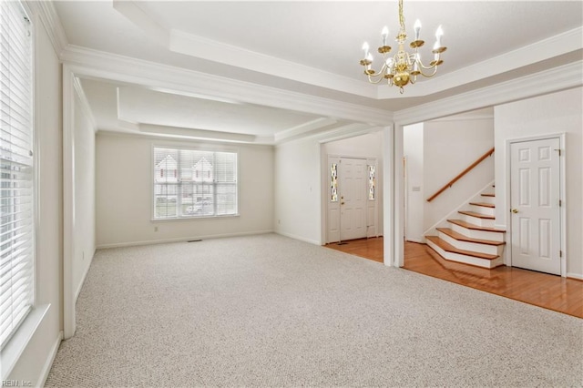 entryway featuring a raised ceiling, light carpet, and an inviting chandelier