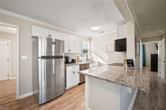 kitchen featuring white cabinetry, light stone counters, kitchen peninsula, a textured ceiling, and appliances with stainless steel finishes