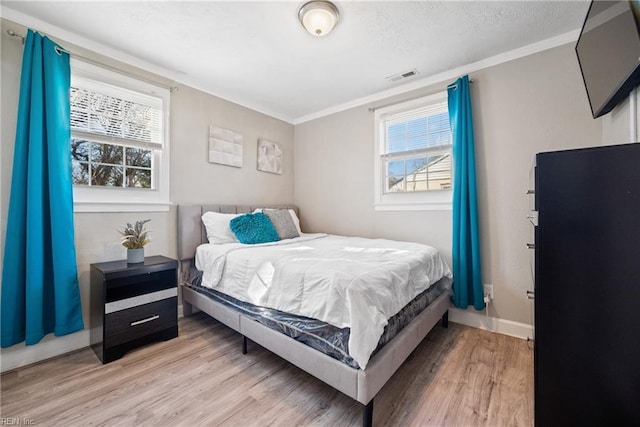 bedroom with hardwood / wood-style flooring, crown molding, and multiple windows