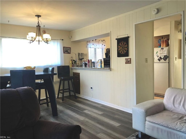 dining room featuring wood walls, dark hardwood / wood-style flooring, and a chandelier