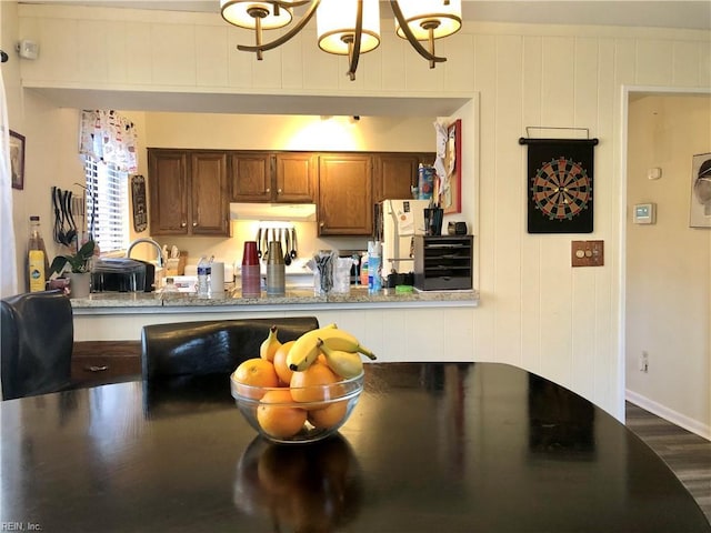 kitchen with dark wood-type flooring, white refrigerator, sink, wooden walls, and beverage cooler