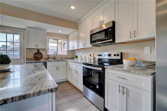 kitchen featuring light stone countertops, white cabinetry, sink, stainless steel appliances, and light hardwood / wood-style flooring