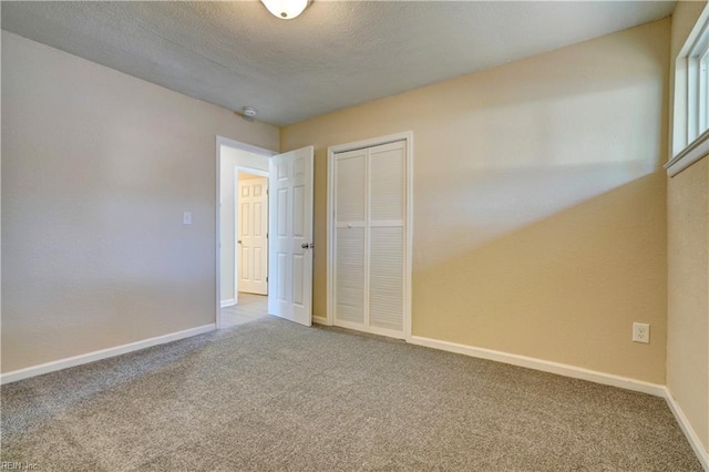 unfurnished bedroom featuring carpet flooring, a textured ceiling, and a closet