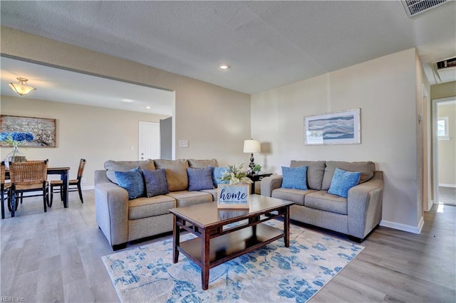 living room with light hardwood / wood-style floors and a textured ceiling