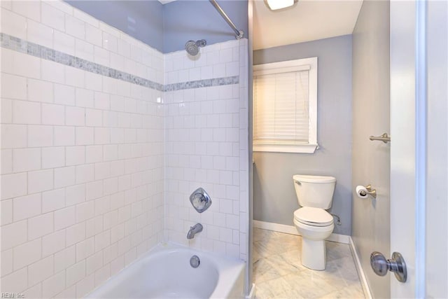 bathroom featuring tiled shower / bath combo and toilet