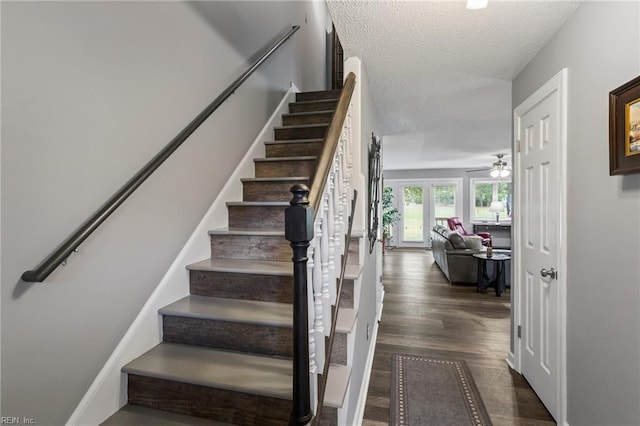 stairs featuring hardwood / wood-style floors, a textured ceiling, and ceiling fan