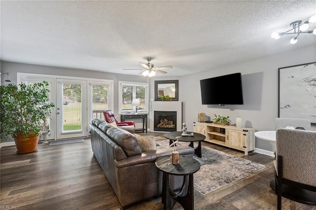 living room with a textured ceiling, ceiling fan with notable chandelier, and dark hardwood / wood-style flooring