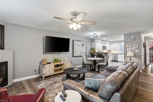 living room with hardwood / wood-style flooring, ceiling fan, and a textured ceiling