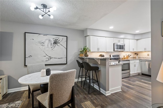 dining area with a textured ceiling, dark hardwood / wood-style flooring, and a notable chandelier