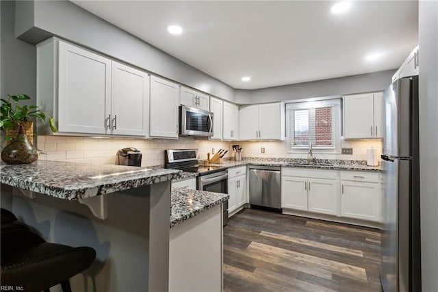 kitchen featuring kitchen peninsula, dark stone countertops, white cabinets, and stainless steel appliances