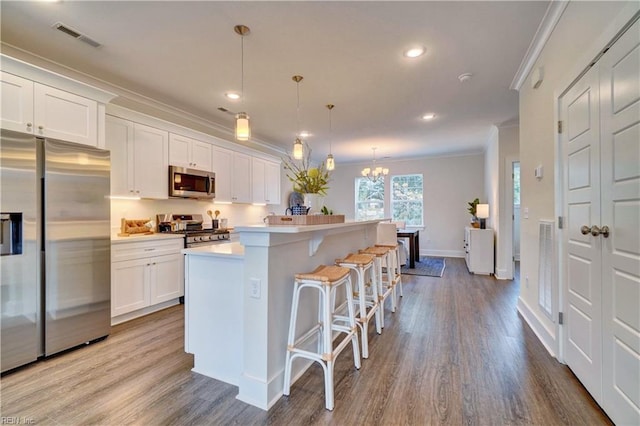 kitchen featuring white cabinetry, a center island, pendant lighting, and appliances with stainless steel finishes