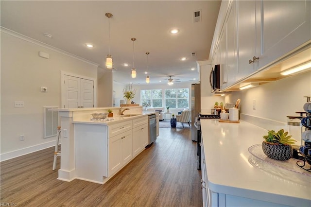 kitchen featuring a center island with sink, sink, hanging light fixtures, stainless steel dishwasher, and wood-type flooring