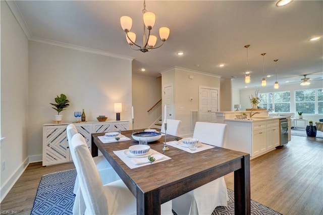 dining room featuring ornamental molding, ceiling fan with notable chandelier, dark wood-type flooring, and sink