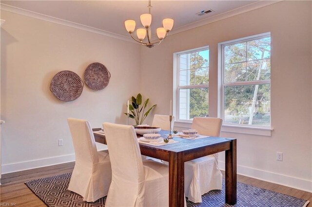 dining area featuring a chandelier, dark wood-type flooring, and ornamental molding