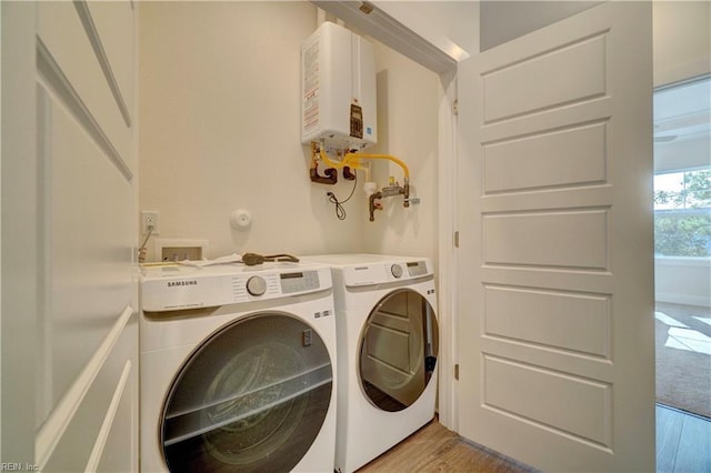 laundry area with independent washer and dryer, light wood-type flooring, and water heater