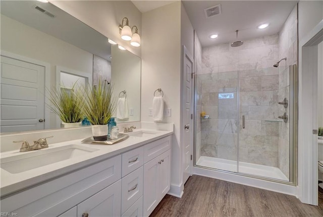 bathroom with hardwood / wood-style floors, vanity, an enclosed shower, and toilet