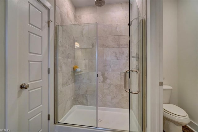 bathroom featuring toilet and a shower with door