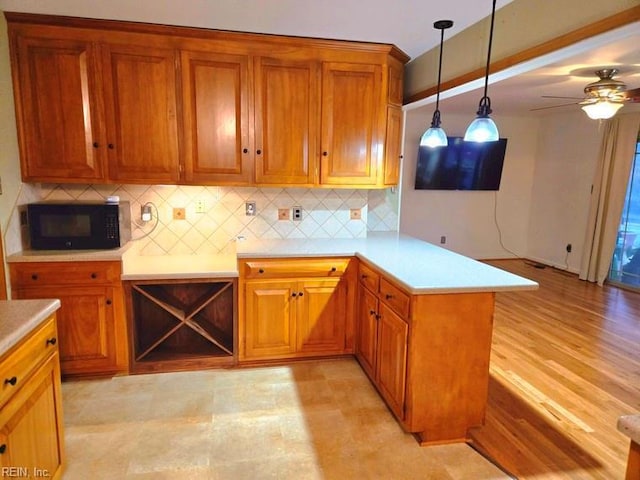 kitchen featuring backsplash, ceiling fan, decorative light fixtures, light hardwood / wood-style floors, and kitchen peninsula