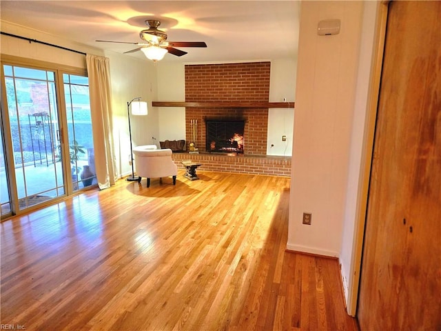 unfurnished living room with a brick fireplace, light hardwood / wood-style flooring, and ceiling fan