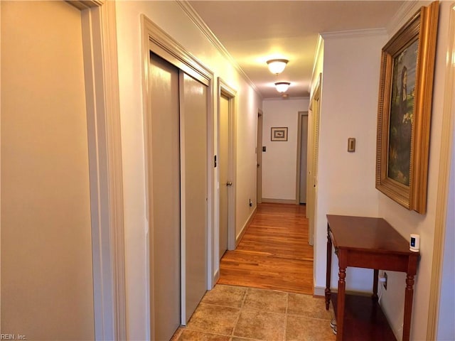 corridor with light hardwood / wood-style floors and crown molding