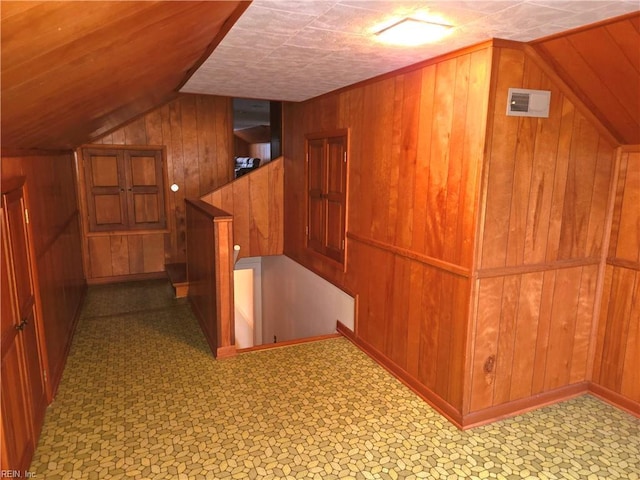 bonus room with wood walls and vaulted ceiling