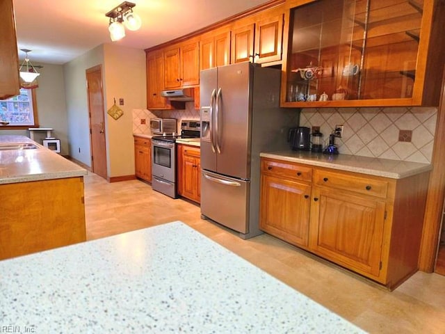 kitchen featuring decorative backsplash, pendant lighting, stainless steel appliances, and sink