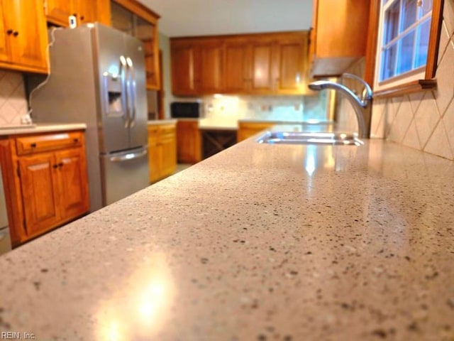 kitchen with decorative backsplash, stainless steel fridge, and sink