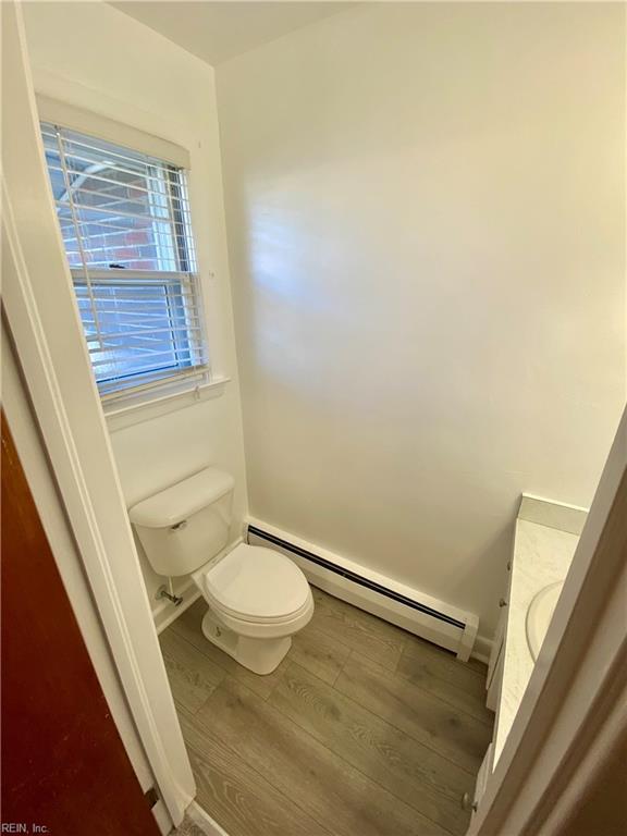 bathroom with hardwood / wood-style floors, vanity, toilet, and a baseboard radiator