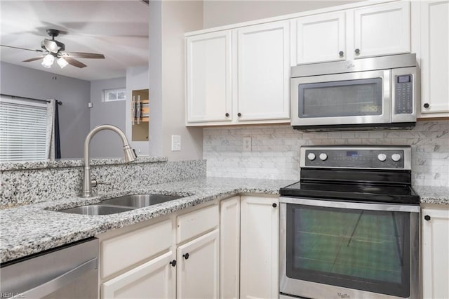 kitchen featuring appliances with stainless steel finishes, backsplash, light stone counters, sink, and white cabinetry