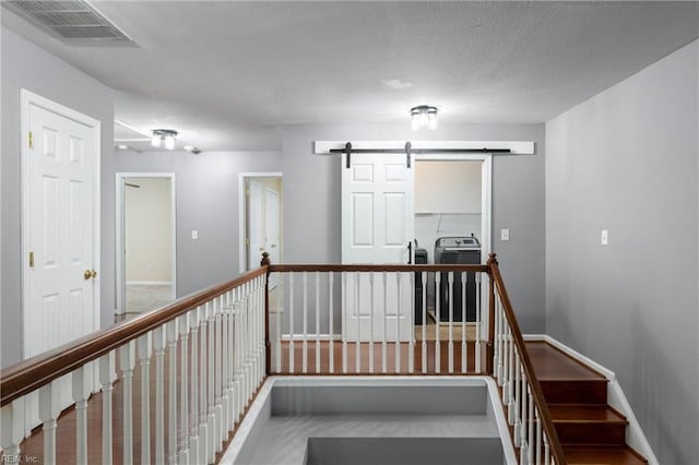 stairway featuring a barn door and a textured ceiling