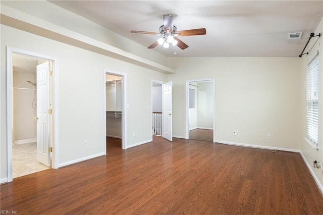 unfurnished bedroom with dark hardwood / wood-style flooring, vaulted ceiling, ceiling fan, a spacious closet, and connected bathroom