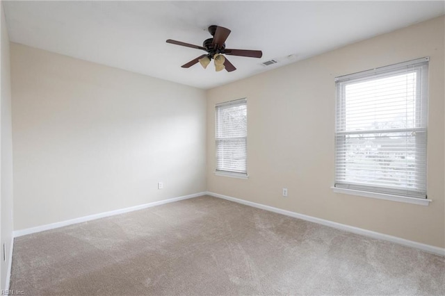 unfurnished room featuring ceiling fan, plenty of natural light, and light colored carpet