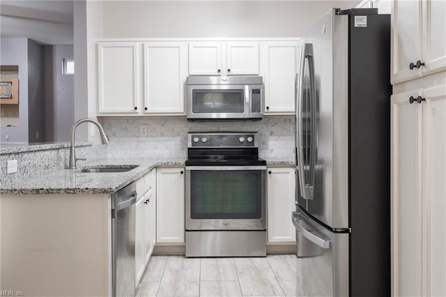 kitchen featuring light stone counters, white cabinetry, sink, and appliances with stainless steel finishes