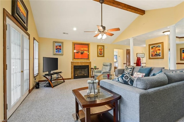 carpeted living room with beam ceiling, decorative columns, a healthy amount of sunlight, and a tiled fireplace