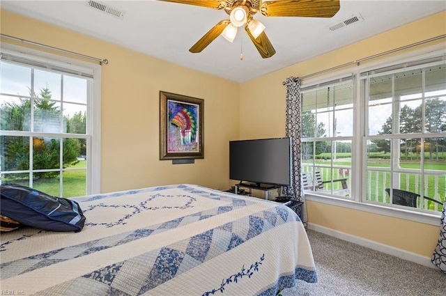 carpeted bedroom featuring ceiling fan and multiple windows