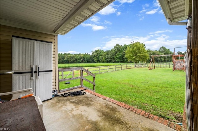 view of yard featuring a playground, a rural view, and a patio