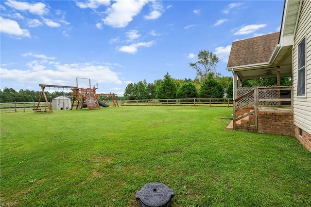 view of yard featuring a rural view, a shed, and a playground