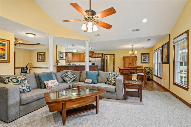 living room featuring ceiling fan with notable chandelier, wood-type flooring, ornate columns, and lofted ceiling