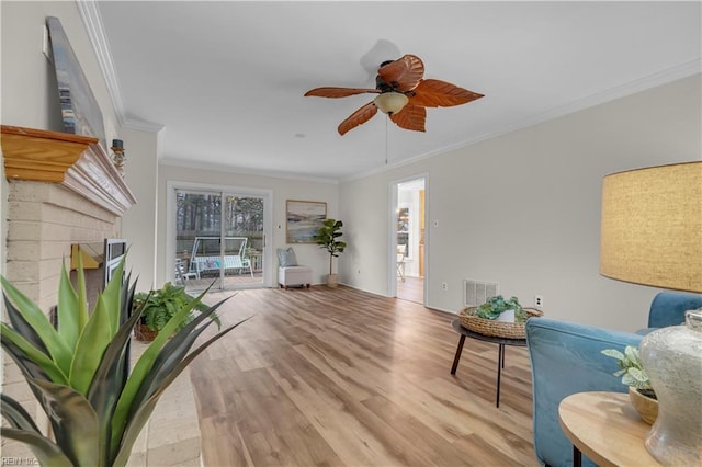 living room with ceiling fan, light hardwood / wood-style floors, ornamental molding, and a fireplace