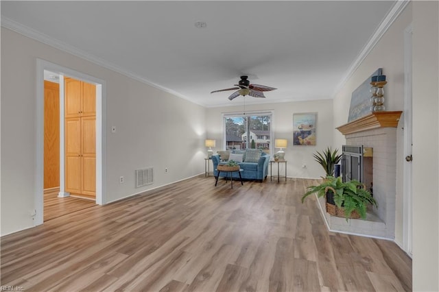 unfurnished room featuring a brick fireplace, ceiling fan, light hardwood / wood-style flooring, and ornamental molding