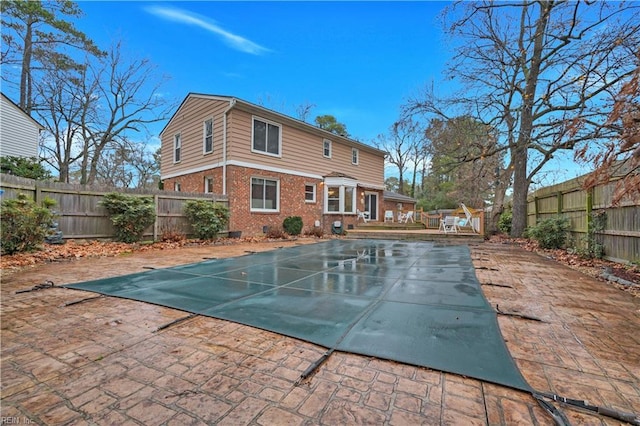 rear view of house with a patio and a covered pool