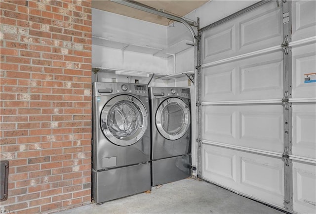 laundry room featuring washing machine and clothes dryer and brick wall