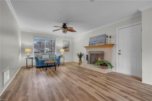 living room featuring crown molding, light hardwood / wood-style flooring, and a brick fireplace