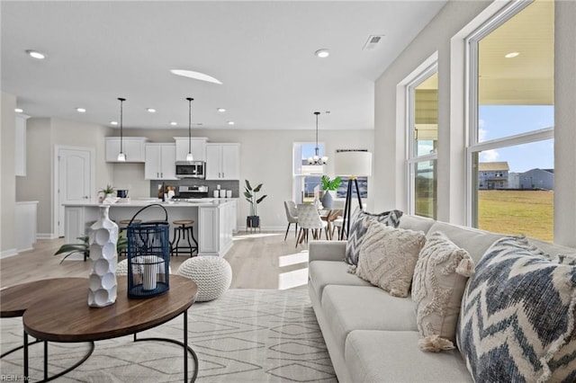 living room with light hardwood / wood-style flooring and a notable chandelier