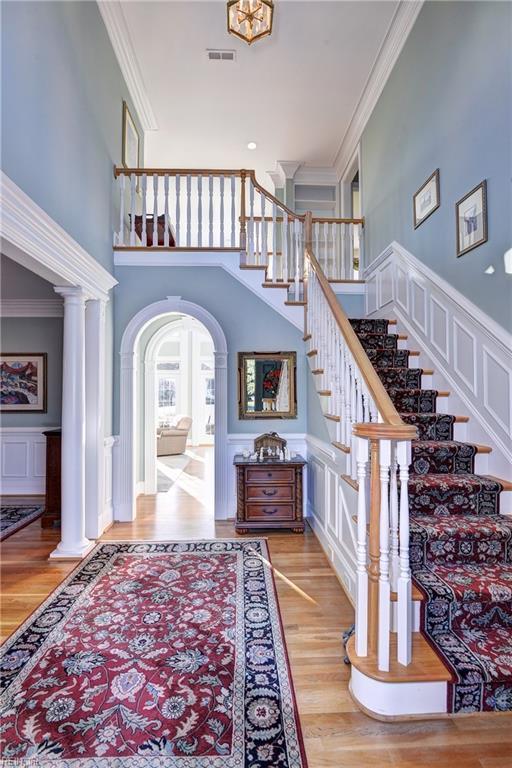 stairway with crown molding, a towering ceiling, and wood-type flooring